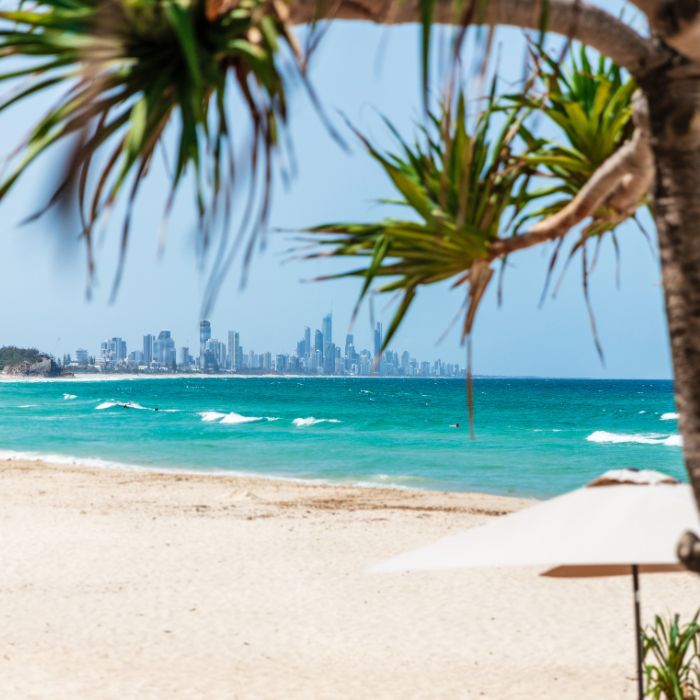 Image of Burleigh Beach on a summer day with clear blue skies, turquoise water, clean sand and Surfers Paradise in the distance.