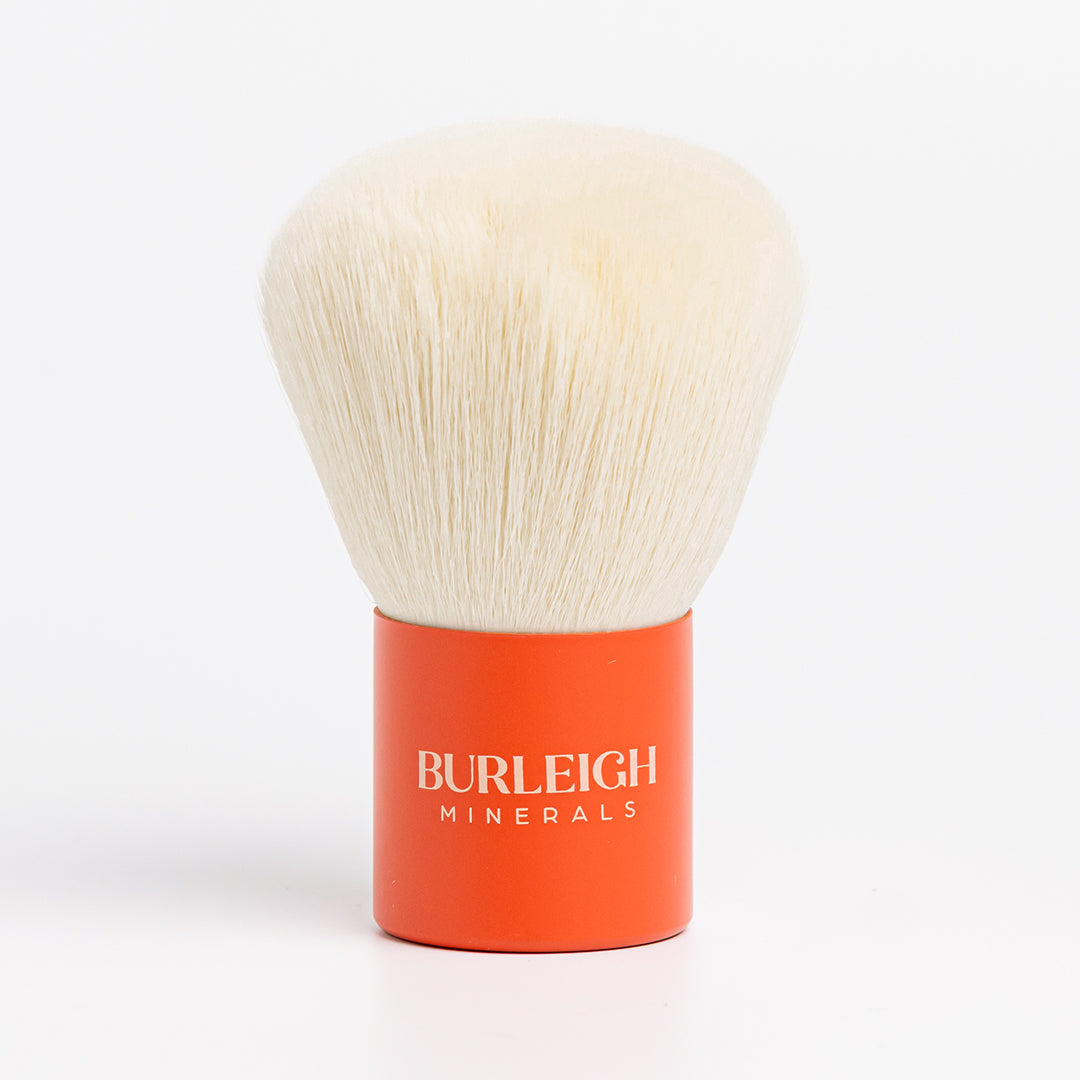 kabuki vegan makeup brush with white bristles and an orange handle